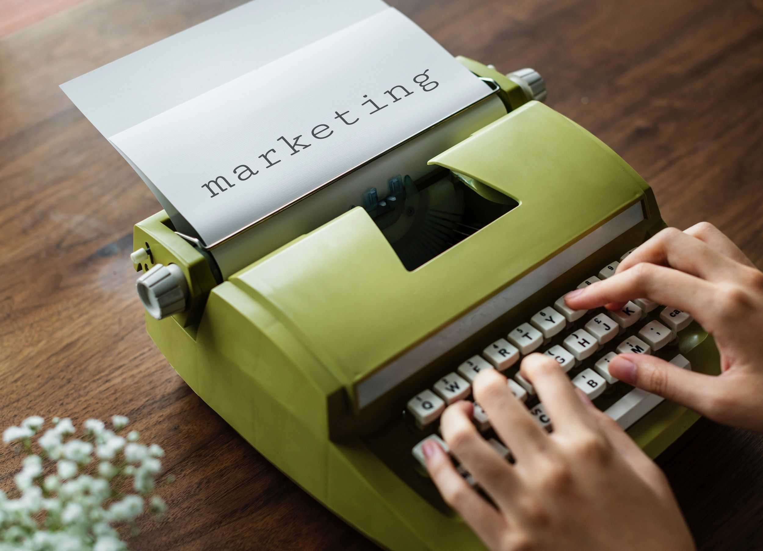 Image of a person typing marketing on a typewriter.